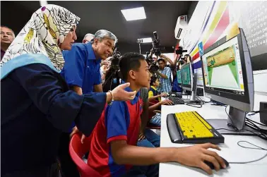  ??  ?? Going
hi-tech: Dr Ahmad Zahid watching student Nazaril Aiman Mohd Razatul Faisal, 14, using a computer after opening the 1Malaysia Internet centres in Kampung Teluk Buluh, Kampung Selekoh and Bagan Datuk.