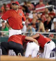  ?? AP/NICK WASS ?? Washington Manager Dusty Baker looks on as outfielder Bryce Harper receives attention after injuring his knee Saturday night. The injury, diagnosed as a bone bruise, happened at first base.