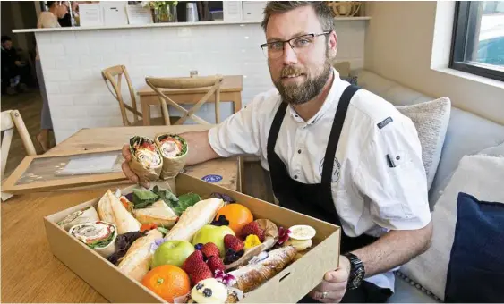  ?? Photo: Nev Madsen ?? TASTY TREATS: Kevin White with one of the picnic hampers on offer at Milk and Honey.