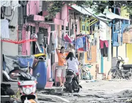  ??  ?? LOCAL COLOUR: Left and right, residents chat and wash clothes in front of their brightly painted houses in Tongkol kampung in Jakarta.