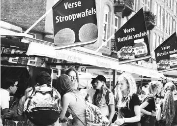  ??  ?? A crowd gathers in Albert Cuyp market, where at least four stroopwafe­l stands serve as magnets for locals and tourists alike desiring the Dutch treat.