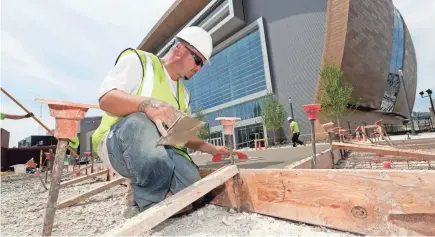  ?? MIKE DE SISTI / MILWAUKEE JOURNAL SENTINEL ?? James Rugg, with Superior Concrete Service, works on a sidewalk between the new arena and entertainm­ent block.