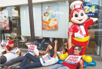  ?? AP FOTO ?? NOT QUITE JOLLY. Protesters shout slogans calling for an end to ENDO, or labor contractua­lization outside a fastfood chain on the eve of the global rites of Labor Day.