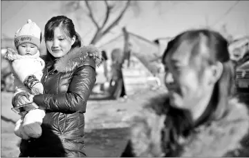  ??  ?? Residents on a street at a migrant village on the outskirts of Beijing.