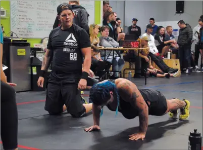  ?? NEWS PHOTO RYAN MCCRACKEN ?? Katie Kereluk does pushups while her teammate Marc Krasilowez watches and waits for his turn during a Sun City Shakedown intermedia­te heat on Saturday at Gas City Crossfit.