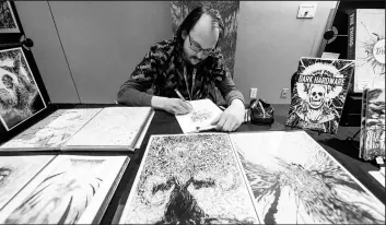  ??  ?? Artist Jonathan LaMantia works on a piece at his booth during the NWI Comic Con on Saturday.