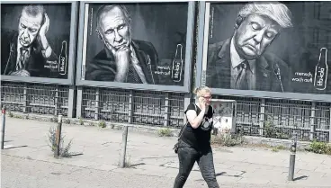 ?? /Reuters ?? Leader board: A woman walks past advertisin­g posters of a German soft-drink producer depicting Turkey’s President Tayyip Erdogan, Russian President Vladimir Putin and US President Donald Trump during the G-20 summit in Hamburg.