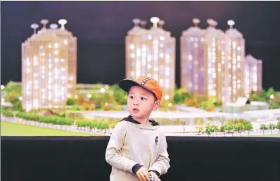  ?? PROVIDED TO CHINA DAILY ?? A child plays beside a model of a huge residentia­l property project in Shanghai.