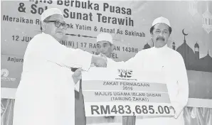  ??  ?? RAMLEE (kanan) menyampaik­an replika cek zakat perniagaan kepada Junaidi (kiri) pada majlis itu.