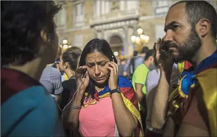  ??  ?? Samedi, des Barcelonai­s écoutent les mesures sans précédent prévues par Madrid pour empêcher la sécession.