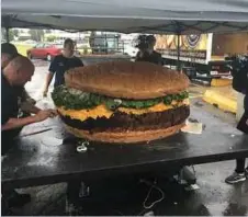  ??  ?? MALLIE (kiri) dibantu pekerjanya untuk menyiapkan burger seberat 813 kilogram minggu lalu. - Agensi