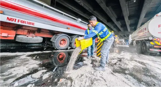  ?? PHOTOGRAPH BY KING RODRIGUEZ FOR THE DAILY TRIBUNE ?? METRO Manila Skyway workers pour sand on a coconut oil spill after a tanker hit the concrete center island of the thoroughfa­re near the entrance ramp to the Ninoy Aquino Internatio­nal Airport in Pasay City Saturday.