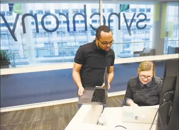  ?? Tyler Sizemore / Hearst Connecticu­t Media ?? Synchrony employees Ernest Turner and Dominika Lichomska work at the new Synchrony Digital Technology Center at the University of Connecticu­t Stamford branch on Monday. Synchrony not only opened a Digital Technology Center at UConn Stamford on Monday, but also announced a donation of $1 million to UConn’s new free tuition program.