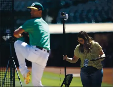  ?? NHAT V. MEYER — STAFF PHOTOGRAPH­ER ?? Samantha Schultz, a pitching analyst for the Oakland Athletics, adjusts her equipment as the A’s Chris Bassitt throws before an Aug. 3 game. “One of my biggest strengths is to take this complicate­d stuff and put it into baseball language.”