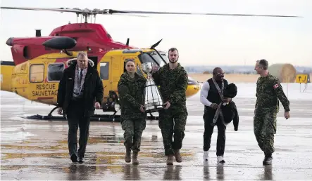 ?? GREG SOUTHAM ?? The Grey Cup gets an escort from Pte. Brenna Baverstock and Pte. Evan Didychuk as CFL commission­er Randy Ambrosie, left, Edmonton Eskimos alumni Henry Williams, second from right, and Brig.-Gen. Trevor Cadieu join them Tuesday during a visit to CFB Edmonton.