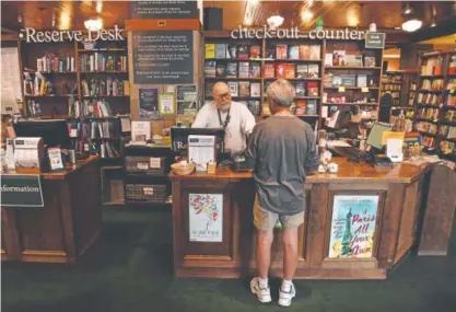  ?? Andy Cross, The Denver Post ?? Mark Lehnertz, manager of the Tattered Cover Book Store in Littleton, helps customer Elton Strittmate­r on Friday. The four Tattered Cover stores officially change hands Saturday.