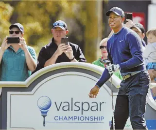  ?? STAFF PHOTO BY ?? MAIN ATTRACTION: Fans look on as Tiger Woods watches his tee shot on the 14th hole during yesterday’s pro-am at the Valspar Championsh­ip.