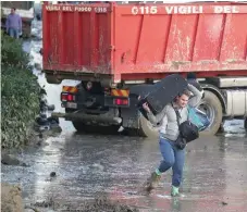  ?? Reuters ?? A man carries baggage as he walks through a street covered in mud, following a landslide on the Italian holiday island of Ischia, Italy, on Sunday. —