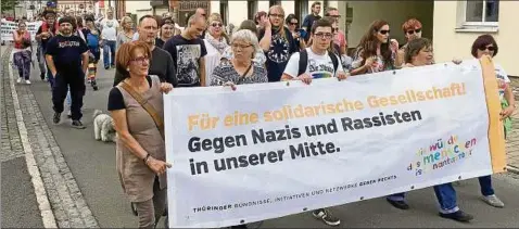  ??  ?? Teilnehmer einer Protestakt­ion gegen ein Neonazi-konzert laufen am Samstag mit einem Plakat durch Themar. Erst vor zwei Wochen hatten rund  Anhänger der rechten Szene aus dem In- und Ausland in der Stadt ein Konzert besucht. Foto: Sebastian Haak, dpa