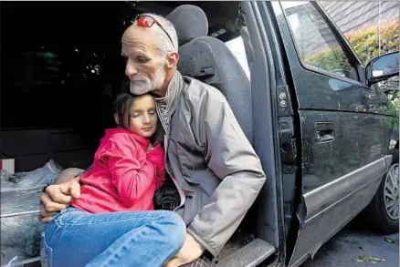  ?? Photog r aphs by Genaro Molina Los Angeles Times ?? THOMAS GOODWIN holds his 7- year- old daughter Leilani in March in the van where they have been living while homeless. A program places such vehicles in spaces in 20 city, county, church, nonprofit agency and industrial lots in Santa Barbara and Goleta.