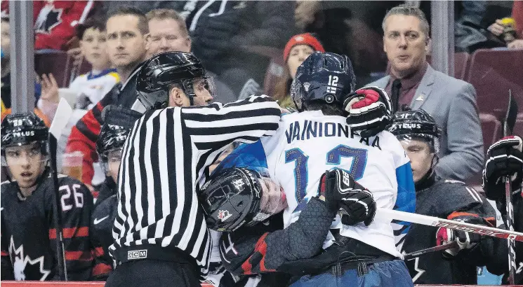  ?? — THE CANADIAN PRESS FILES ?? Canada’s Maxime Comtois tangles with Finland’s Samuli Vainionpaa during exhibition play. The Finns later eliminated Canada from the event.