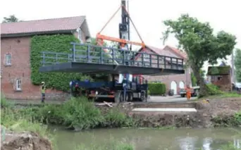  ?? FOTO DIRK ROEFFLAER ?? Bij het plaatsen van de brug werd het dakje boven de poort van de molen geraakt. Het duurde 2,5 uur voor de brug op de sokkels stond.