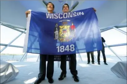  ?? MIKE DE SISTI — MILWAUKEE JOURNAL-SENTINEL VIA AP ?? Foxconn Chairman Terry Gou, left, and Gov. Scott Walker hold the Wisconsin flag to celebrate their $10 billion investment to build a display panel plant in Wisconsin, at the Milwaukee Art Museum in Milwaukee, Wis., Thursday.