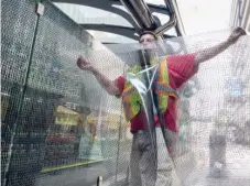  ??  ?? Miguel Lagos applies film to the glass panels of a Loop Link station on Madison Street on Wednesday. The moire patterns that will decorate the station were designed by Christine Tarkowski.