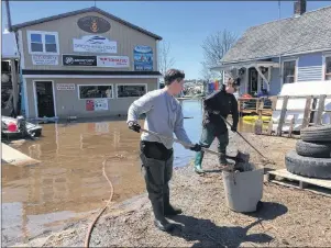  ?? CP PHOTO ?? Danielle Ring, 23, (left) and her sister Rebecca, 20, shovel debris out of water that flooded the front driveway of their father’s boat service business in Saint John, N.B., on Tuesday