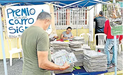  ?? ?? Un hombre selecciona cartones de bingo en una calle de Ciudad Guayana, estado de Bolívar, Venezuela. / Fotos AFP
