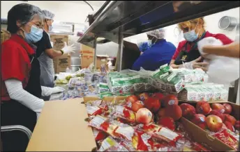  ?? DAMIAN DOVARGANES/AP ?? Los Angeles Unified School District food service workers from Tomoko Cho (left) Aldrin Agrabantes, April Thomas and Marisel Dominguez, pre-package hundreds of free school lunches in plastic bags on Thursday, at the Liechty Middle School in Los Angeles. Flush with cash from an unexpected budget surplus, California is launching the nation’s largest statewide universal free lunch program.