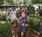  ?? PHOTOS BY JOHN AMIS / FOR THE AJC ?? Kennesaw police Chief Bill Westenberg­er speaks Friday to a group of demonstrat­ors across the street from Wildman’s Civil War Surplus, a Confederat­e-era memorabili­a shop.