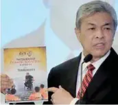  ??  ?? Ahmad Zahid showing Malaysia’s deradicali­sation book during his speech at the dialogue yesterday.