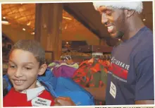  ?? STAFF PHOTO BY MATT WEST ?? New England Patriot Devin McCourty helps Miguel Guerrero try on a jacket as Patriots players treat local kids to a Christmas shopping spree at Bass Pro Shops at Patriot Place yesterday.