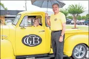  ?? Tim Godbee ?? Calhoun branch president Donna McEntyre (left), sits in a classic GMC truck during Saturday’s grand reopening event as Greater Community Bank President David Lance shields both from the rain. The branch is now full back open to the public.