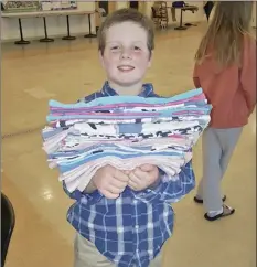  ?? Meg Hydock photo via AP ?? Gibson Griffith, 10, of Lee, N.H., holds a stack of fabric crate liners he and others sewed Sunday to send to wildlife injured in wildfires in Australia. Griffith, who organized a sewing party, is among thousands of people worldwide who have been making everything from bat wraps to kangaroo joey pouches for the animals affected by the wildfires.