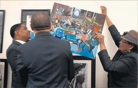  ?? Photograph­s by Joe Raedle Getty Images ?? REPS. CEDRIC RICHMOND (D-La.), William Lacy Clay (D-Mo.) and Alma Adams (D-N.C.) rehang a painting on Tuesday that was removed from a Capitol wall by Rep. Duncan Hunter (R-Alpine) because he found its depictions of police officers as pigs offensive.