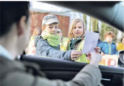  ?? RP-FOTO: KÖHLEN ?? Ole (7) und Rebecca (8) von der Grundschul­e Unterhaan verteilen „Denkzettel“an Eltern, die ihre Kinder mit dem Wagen zur Schule bringen.