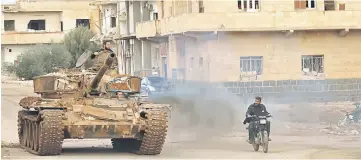  ??  ?? Rebel fighters drive a tank in a street in the city of Daraa, in southern Syria. — AFP photo