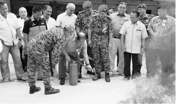  ??  ?? Nyalau trying his hand at using a fire extinguish­er at the event yesterday.