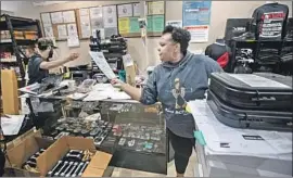  ?? Brian van der Brug Los Angeles Times ?? GENEVA SOLOMON works through a crush of paperwork for purchases at Redstone Firearms in Burbank. She says sales have more than doubled since March.