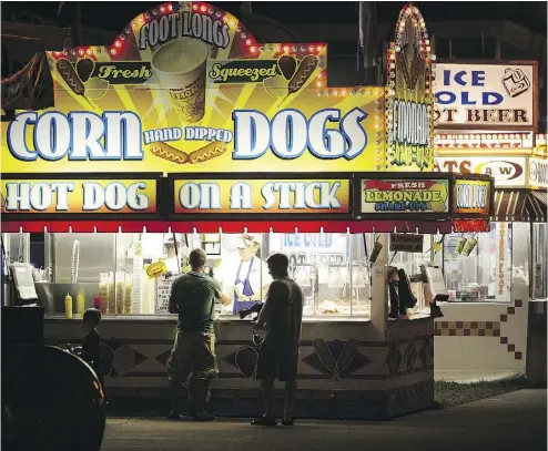  ?? SCOTT OLSON / GETTY IMAGES ?? Fairgoers hit the corn dog stand at the Iowa State Fair this week in Des Moines. The event is expected to draw one million people. Fairs seem to appeal to the yearning for something familiar, for simpler times.