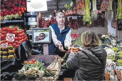  ?? MANU MITRU ?? Una clienta compra verduras y hortalizas, en un puesto de mercado.