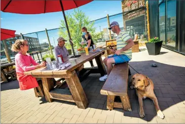  ?? Herald photo by Ian Martens ?? Server Julia Anton brings lunch to Val and Bill Loewen, along with their son Kyle and his dog Bennett, Thursday on the patio at Coulee Brew Co. during the first day of the province's relaunch. @IMartensHe­rald