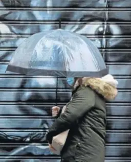  ?? JAVIER ALBIÑANA ?? Una mujer se protege de la lluvia.