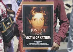  ??  ?? A woman holds a poster with a portrait of Asifa