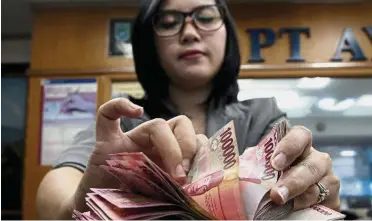  ?? — EPA ?? Tumbling rupiah: A teller counts rupiah bank notes at a money changer in Jakarta. The currency slipped another 0.2% yesterday to 14,625 to the US dollar, quickly shrugging off a surprise rate increase by the central bank the previous day.