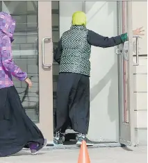  ?? JUSTIN TANG/THE CANADIAN PRESS FILES ?? A woman puts her hand through a missing pane of glass, broken by vandals, as people enter a mosque in Ottawa. According to StatsCan, hate crimes against Muslims went up in 2013.
