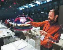  ?? REUTERS ?? A member of the media takes his food from a robotic delivery machine in the Games’ Main Press Center’s dining hall in Beijing on Thursday.