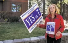  ??  ?? Peggy Bourland, a leader in the group seeking to ban shortterm rentals, carries a lawn sign promoting the measure.